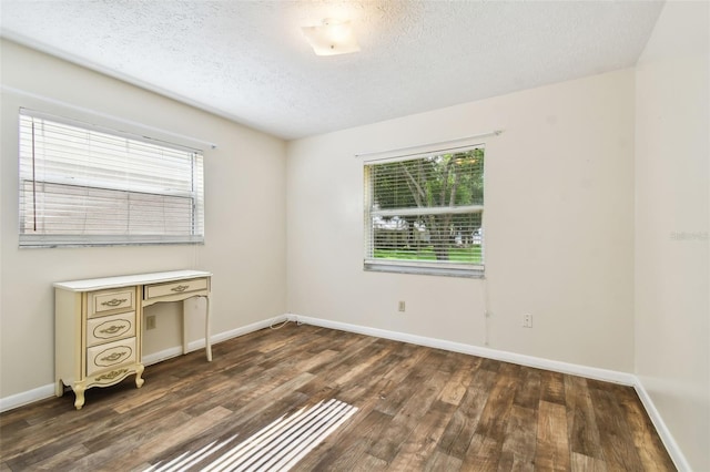 unfurnished room with a wealth of natural light, dark wood finished floors, and baseboards