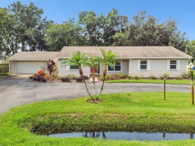 ranch-style house featuring a garage, aphalt driveway, and a front yard