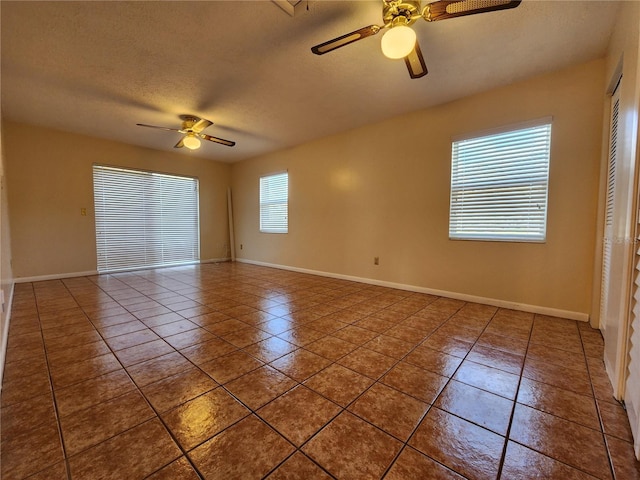 unfurnished room with ceiling fan, a textured ceiling, baseboards, and tile patterned floors