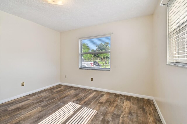 spare room featuring dark wood-style floors, a textured ceiling, and baseboards