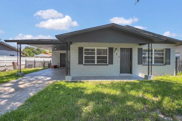 bungalow featuring concrete block siding, fence, driveway, a carport, and a front yard