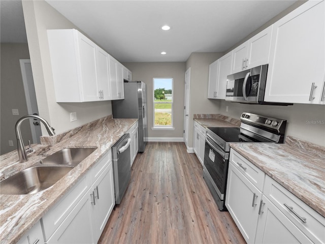 kitchen featuring sink, stainless steel appliances, light wood-type flooring, and light stone countertops