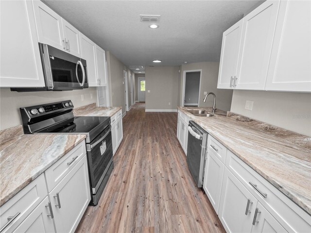 kitchen featuring appliances with stainless steel finishes, light hardwood / wood-style floors, sink, and light stone countertops