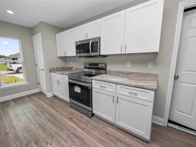 kitchen with white cabinets, light wood-type flooring, and stainless steel appliances