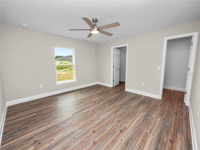 unfurnished bedroom featuring hardwood / wood-style flooring, a closet, a spacious closet, and ceiling fan