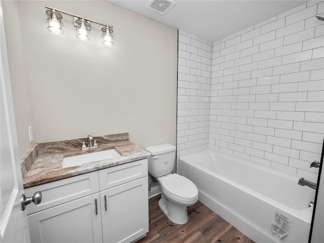 full bathroom featuring tiled shower / bath combo, hardwood / wood-style flooring, toilet, and vanity