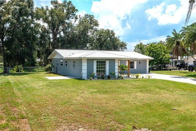 single story home with metal roof, a front lawn, and fence