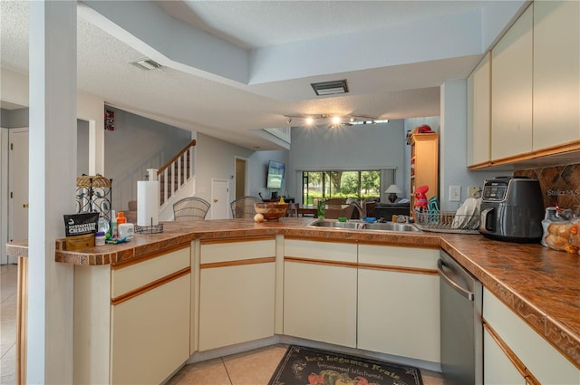 kitchen with light tile patterned floors, sink, kitchen peninsula, and stainless steel dishwasher