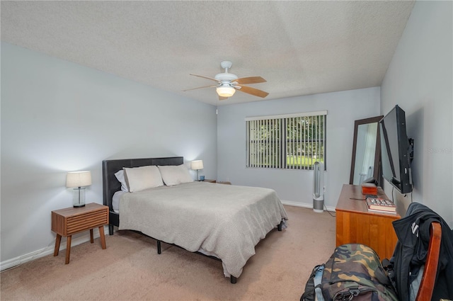 bedroom featuring ceiling fan, light colored carpet, and a textured ceiling