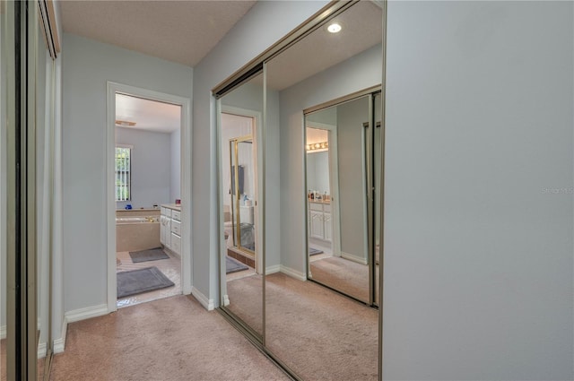 hall featuring light carpet and a textured ceiling