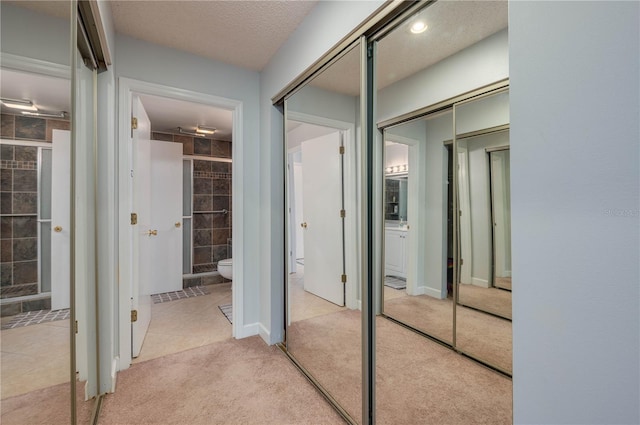 hallway with light colored carpet and a textured ceiling