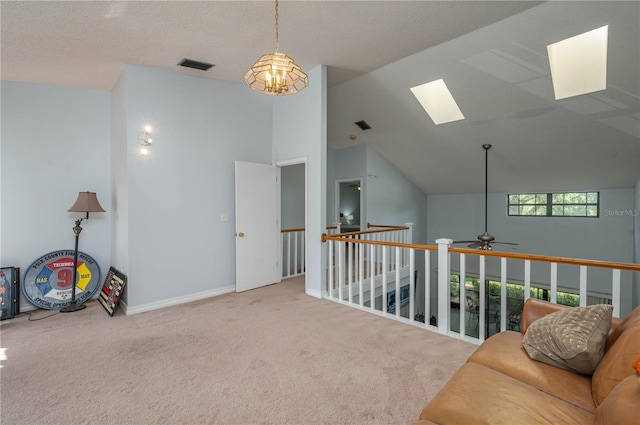 sitting room with ceiling fan with notable chandelier, vaulted ceiling with skylight, light carpet, and a textured ceiling