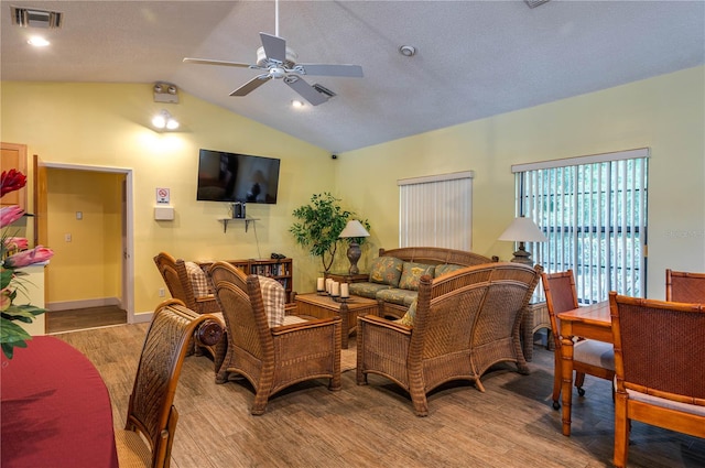 living room with lofted ceiling, ceiling fan, light hardwood / wood-style floors, and a textured ceiling