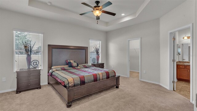 carpeted bedroom featuring a tray ceiling, a closet, a spacious closet, and multiple windows