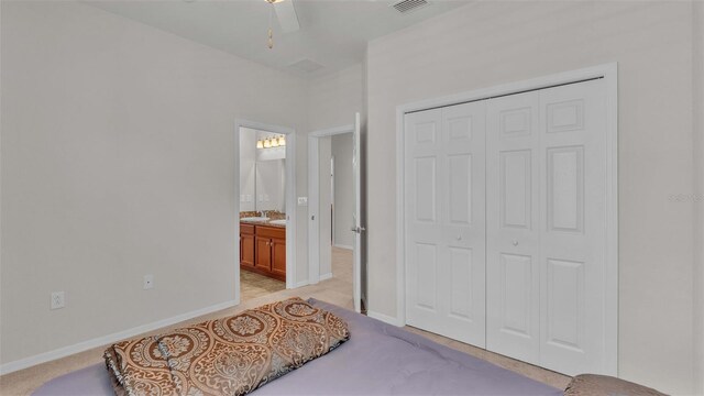 carpeted bedroom with ceiling fan, ensuite bathroom, and a closet