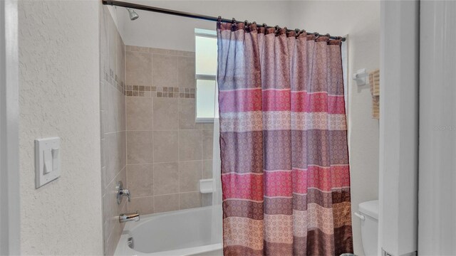 bathroom with toilet and shower / bath combo with shower curtain