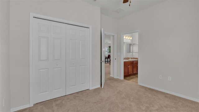 unfurnished bedroom with ensuite bath, light colored carpet, ceiling fan, sink, and a closet