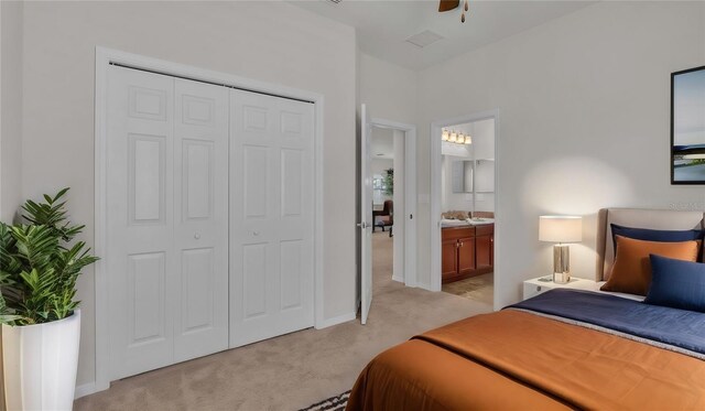 bedroom with ceiling fan, ensuite bath, light carpet, and a closet