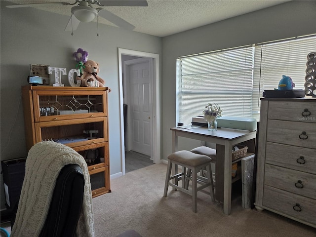 office space featuring light carpet, baseboards, a ceiling fan, and a textured ceiling