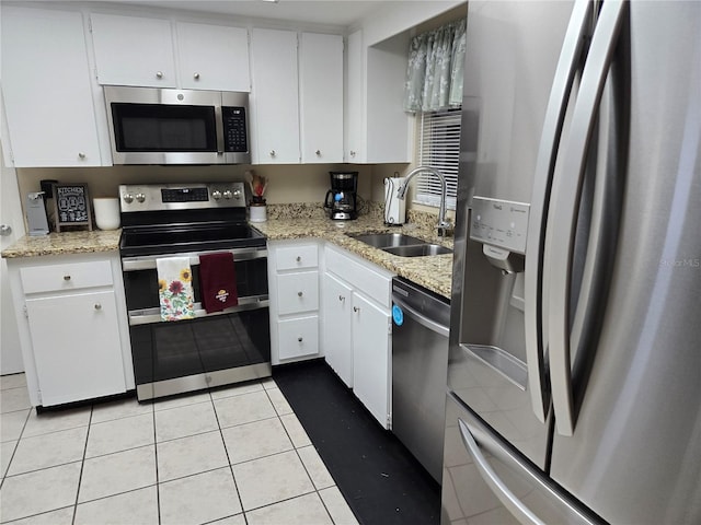 kitchen featuring appliances with stainless steel finishes, light tile patterned flooring, a sink, and white cabinetry