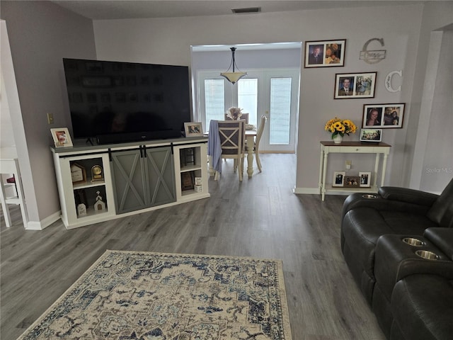 living room featuring baseboards, visible vents, and wood finished floors