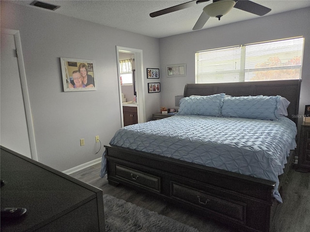 bedroom featuring ceiling fan, a textured ceiling, dark wood-style flooring, visible vents, and baseboards