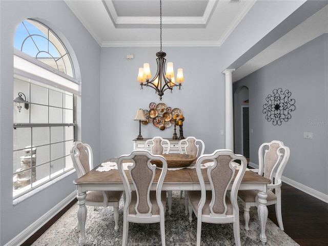 dining space featuring decorative columns, crown molding, a tray ceiling, dark hardwood / wood-style flooring, and a chandelier