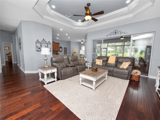 living room with ceiling fan, dark hardwood / wood-style flooring, ornamental molding, and a tray ceiling