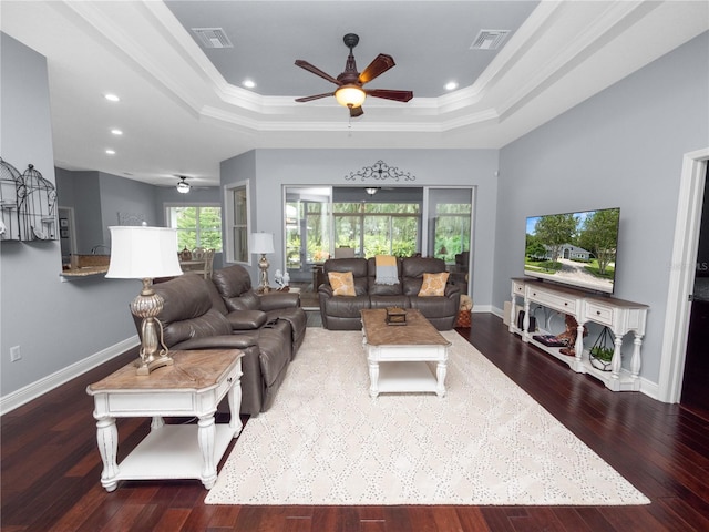 living room with dark hardwood / wood-style floors, ornamental molding, and a tray ceiling