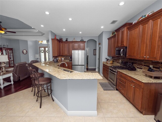 kitchen with sink, stainless steel appliances, kitchen peninsula, a breakfast bar area, and decorative backsplash