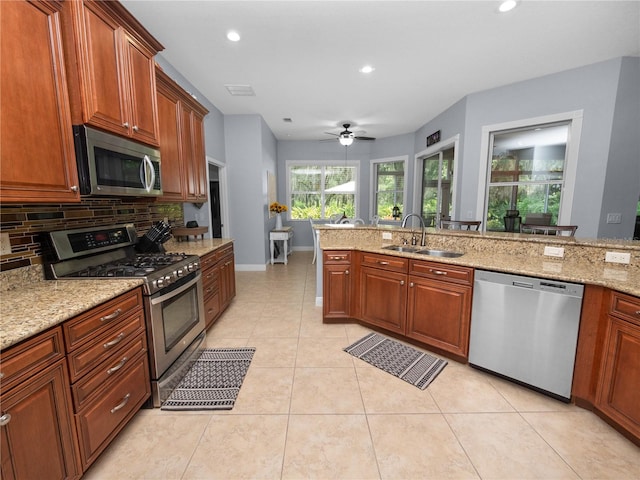 kitchen with ceiling fan, sink, tasteful backsplash, light stone counters, and appliances with stainless steel finishes