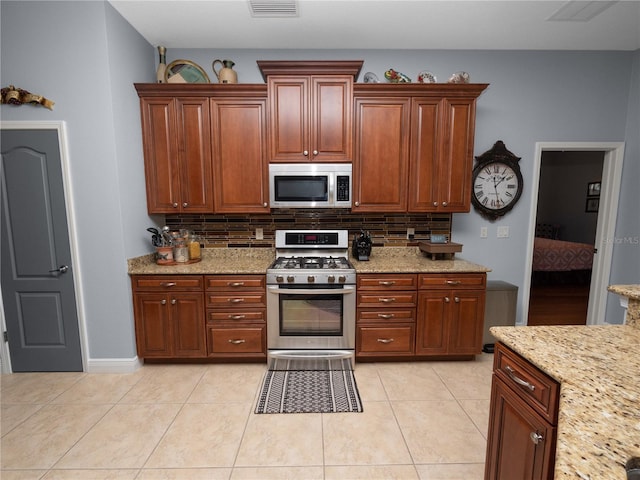 kitchen with tasteful backsplash, light stone countertops, light tile patterned floors, and stainless steel appliances