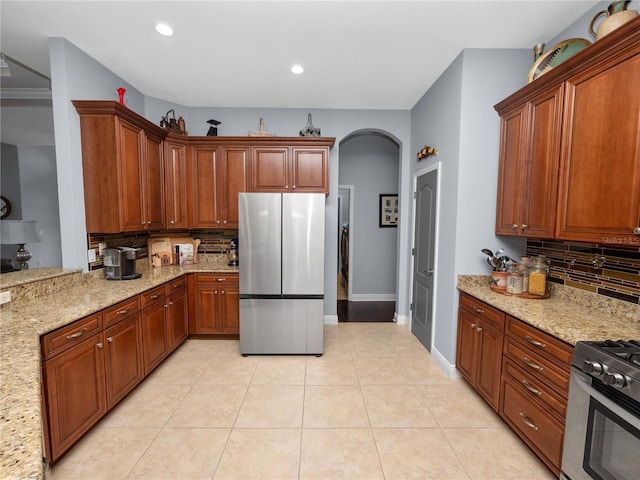 kitchen featuring decorative backsplash, light stone countertops, light tile patterned flooring, and stainless steel appliances