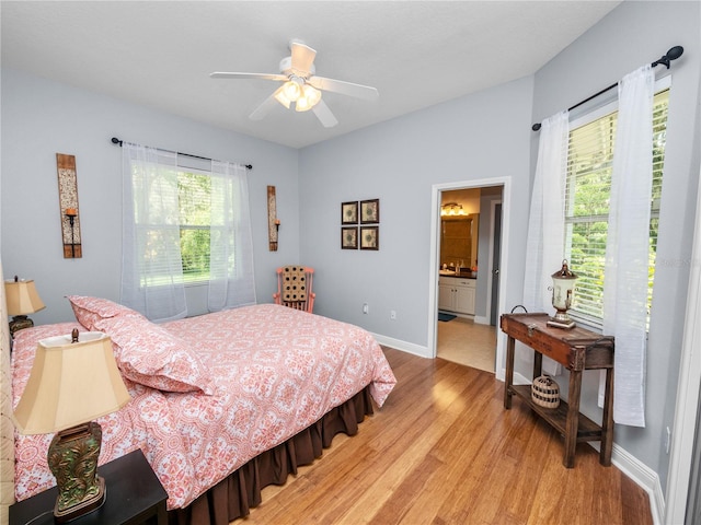 bedroom featuring ceiling fan, light wood-type flooring, connected bathroom, and multiple windows