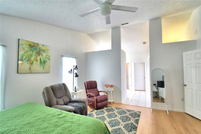 bedroom with a textured ceiling, ceiling fan, and light wood-type flooring