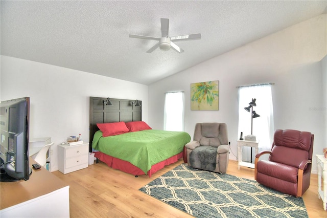 bedroom with a textured ceiling, ceiling fan, light hardwood / wood-style floors, and lofted ceiling