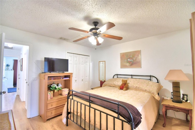 bedroom with light wood-type flooring, ceiling fan, a closet, and a textured ceiling