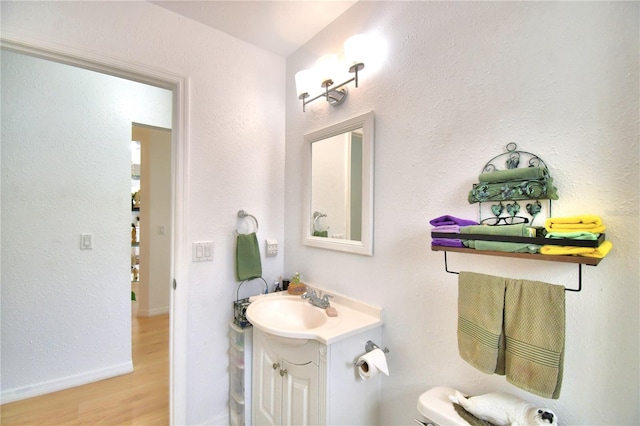 bathroom with toilet, hardwood / wood-style floors, and vanity