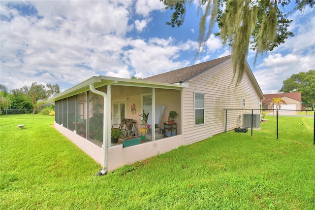 back of property featuring a lawn, a sunroom, and central AC