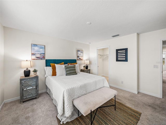 carpeted bedroom with a closet and a spacious closet