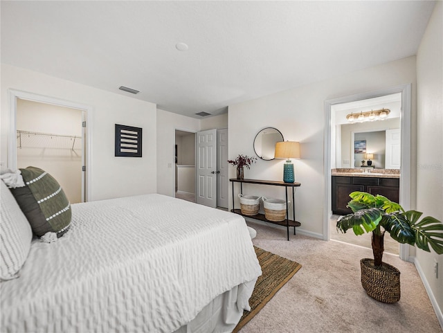 bedroom with ensuite bath, light colored carpet, a closet, and a spacious closet