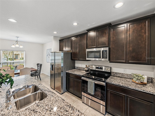 kitchen with appliances with stainless steel finishes, dark brown cabinetry, a chandelier, and sink