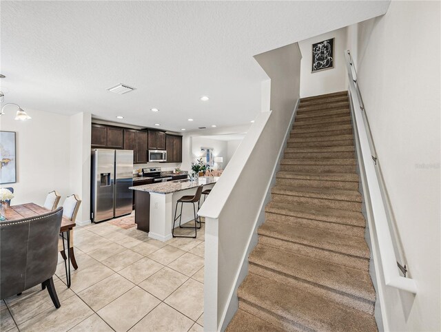 stairs featuring tile patterned floors and a chandelier