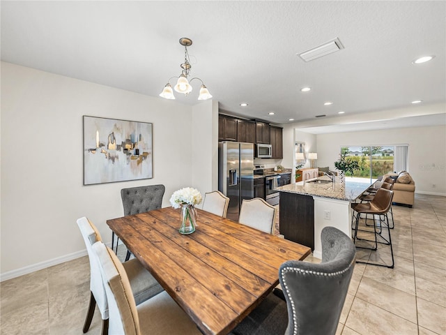 dining space with light tile patterned floors, a chandelier, and sink