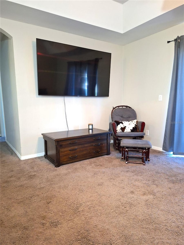 living room featuring arched walkways, carpet flooring, and baseboards