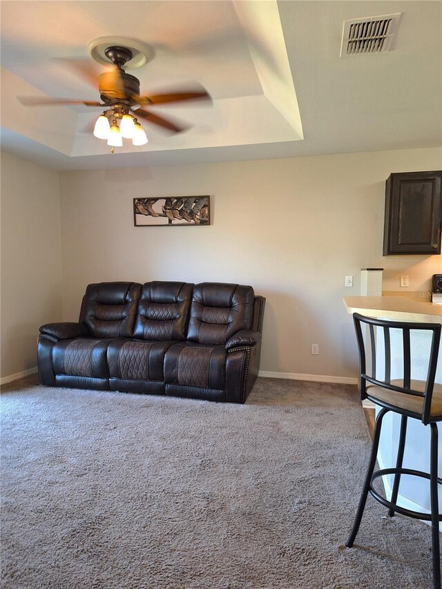 carpeted living room featuring a tray ceiling and ceiling fan