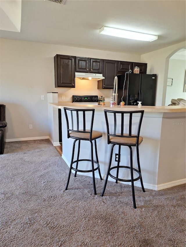 kitchen featuring black refrigerator with ice dispenser, dark brown cabinets, stove, a breakfast bar, and light carpet