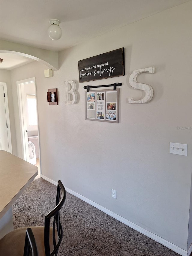 carpeted dining room with baseboards and arched walkways