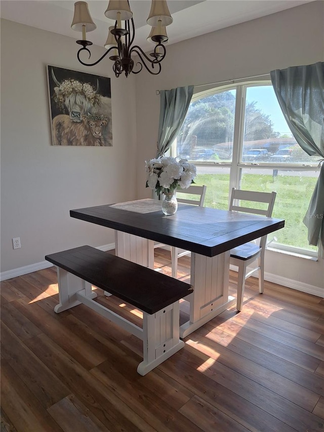 dining space featuring a chandelier, wood finished floors, and baseboards