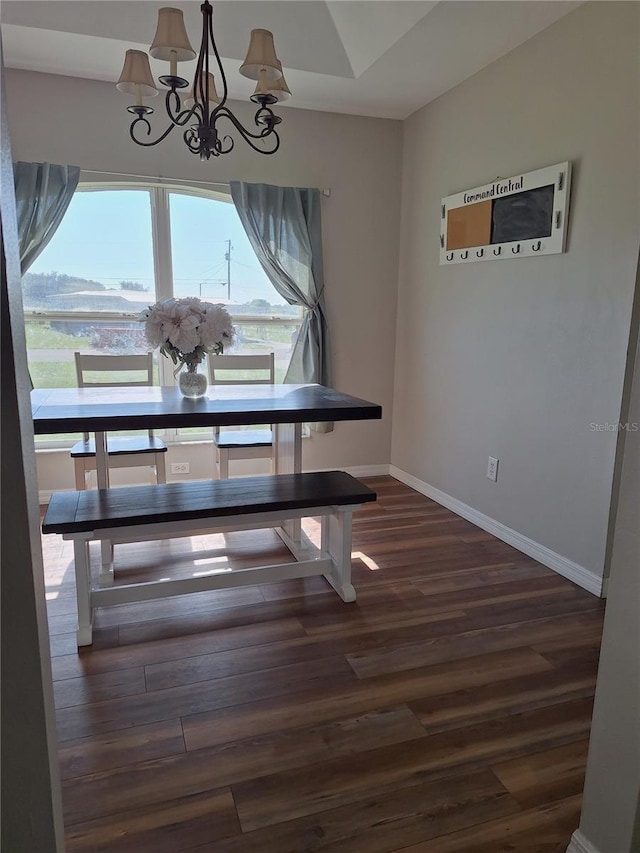 dining room with a chandelier, dark wood-type flooring, and baseboards